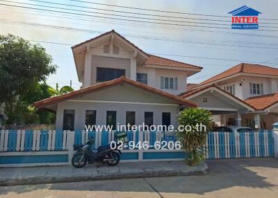 Spacious two-story house with a blue fence and motorcycle parked outside