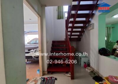 Interior view of a home entrance with red staircase and visible car in the background