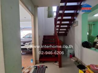 Interior view of a home entrance with red staircase and visible car in the background