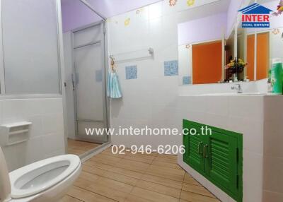 Bright and colorful bathroom with green cabinet doors and wooden floor