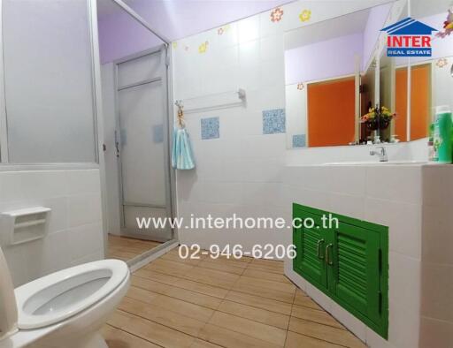 Bright and colorful bathroom with green cabinet doors and wooden floor