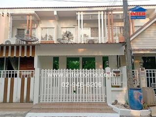 White two-story townhouse with balcony and gated entrance