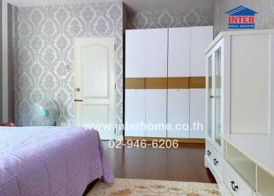 Spacious bedroom with elegant wallpaper and large white wardrobe