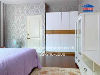 Spacious bedroom with elegant wallpaper and large white wardrobe