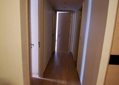 Narrow residential hallway with wooden flooring and multiple doors