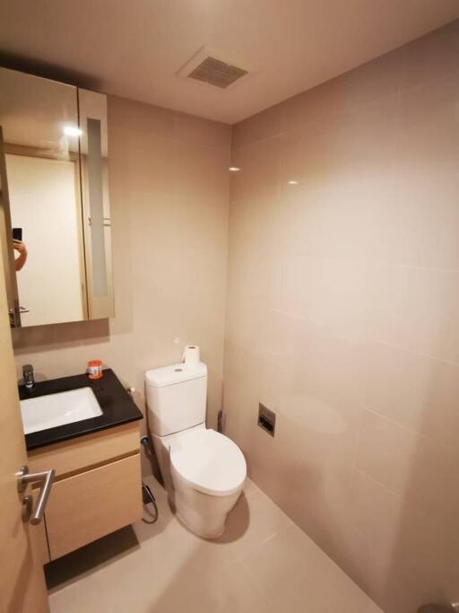 Modern bathroom with sleek design featuring a wall-mounted sink, mirror, and built-in toilet