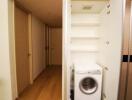 Compact laundry area with washing machine and storage under staircase