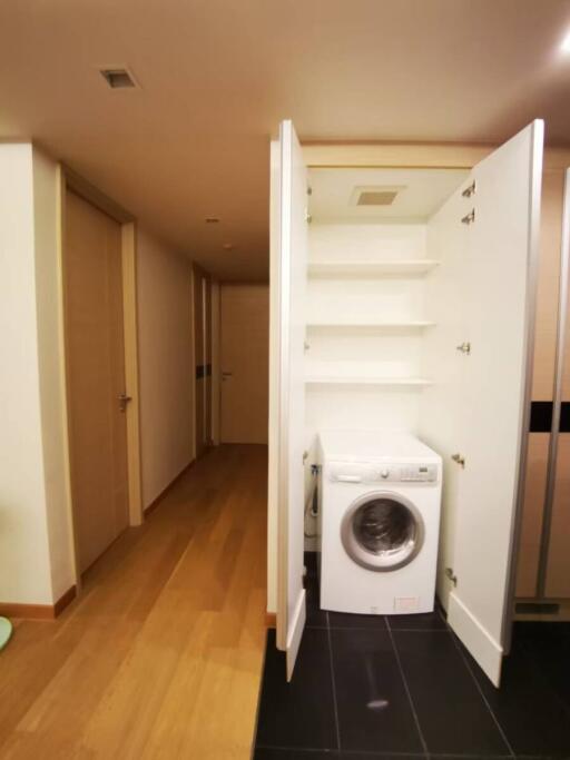 Compact laundry area with washing machine and storage under staircase