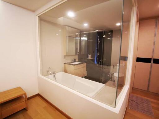 Elegant modern bathroom with large bathtub visible through glass partition