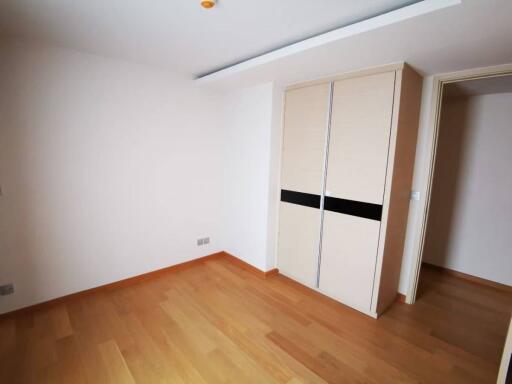 Minimalist bedroom with wooden flooring and built-in wardrobe