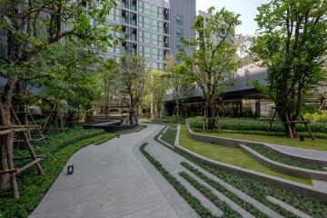 Modern outdoor garden with pathway and seating area next to a residential building