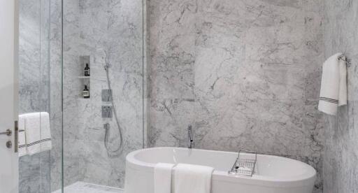 Modern bathroom with marble walls, glass shower, and freestanding bathtub