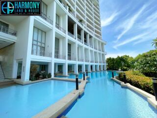 Luxurious condominium building with an outdoor swimming pool surrounded by lush greenery