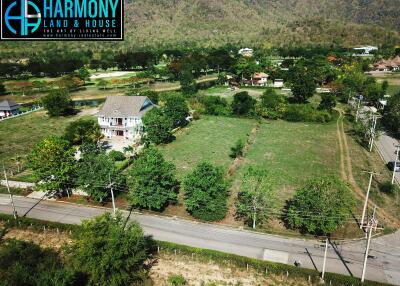 Aerial view of a spacious property with house and large garden near mountains