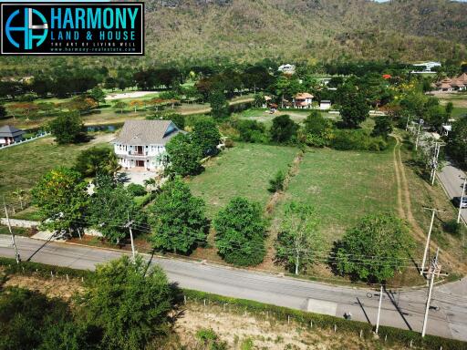 Aerial view of a spacious property with house and large garden near mountains