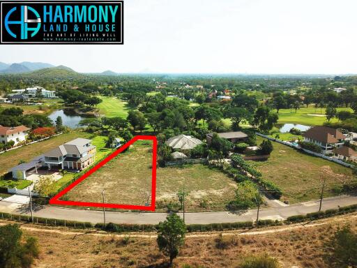 Aerial view of a spacious property for sale bordered by roads and neighboring homes with a scenic mountain backdrop