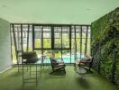 Spacious living room with floor-to-ceiling windows overlooking a pool and a vibrant vertical garden
