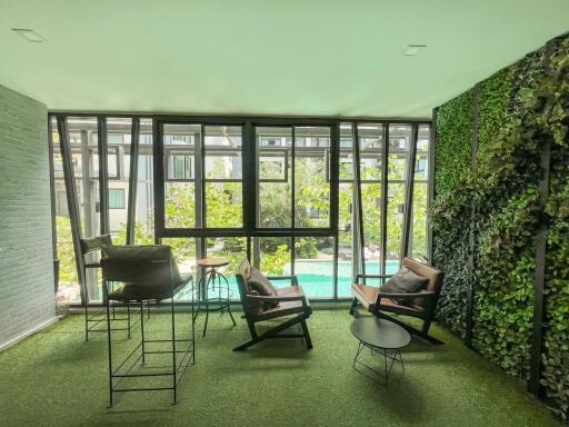 Spacious living room with floor-to-ceiling windows overlooking a pool and a vibrant vertical garden