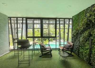 Spacious living room with floor-to-ceiling windows overlooking a pool and a vibrant vertical garden