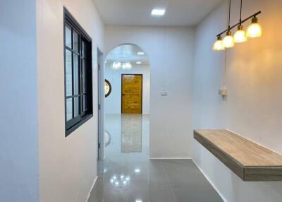 Elegant residential hallway with polished tile flooring, modern lighting, and wooden door