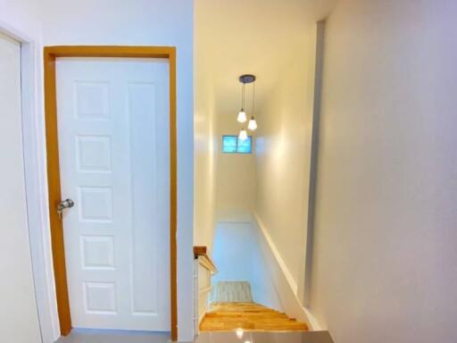 Brightly lit hallway with wooden stairs and decorative hanging light