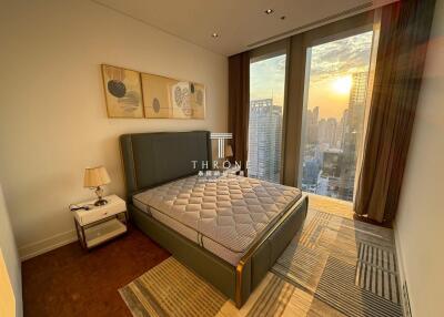 Modern bedroom with large windows and cityscape view at sunset