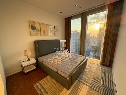 Modern bedroom with large windows and cityscape view at sunset