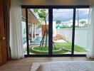 Modern bedroom with a view of a pool and garden through large glass doors