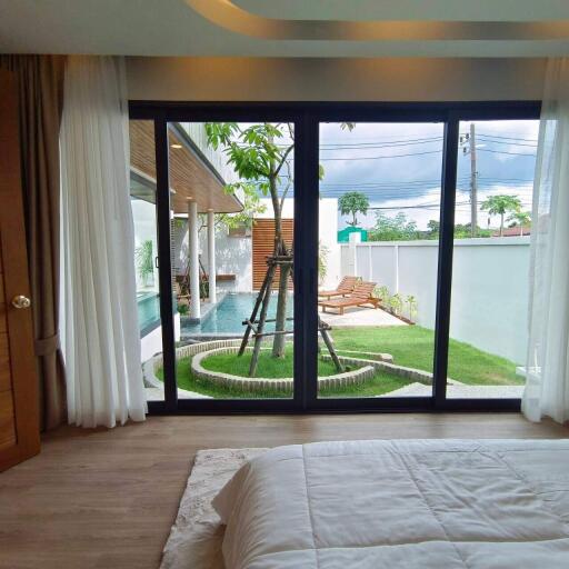 Modern bedroom with a view of a pool and garden through large glass doors