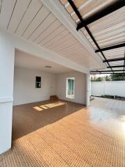 Spacious covered patio area with tiled flooring and adjacent garden