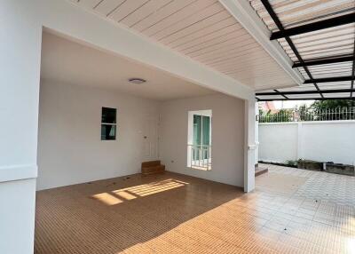 Spacious covered patio area with tiled flooring and adjacent garden