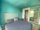 Bright bedroom with turquoise walls and a patterned bedspread