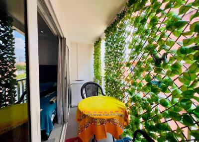 Bright balcony area with lush greenery and outdoor seating