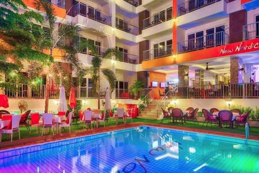 Luxurious hotel building with outdoor pool and dining area at night