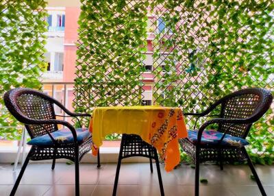 Cozy balcony with green foliage, a table with vibrant cloth, and two chairs