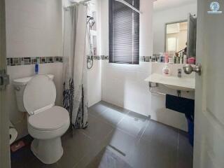 Compact modern bathroom with a shower curtain, toilet, and sink area