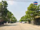 Peaceful street view in a residential area with visible real estate signage and lush green trees