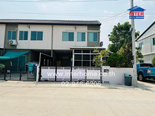 Modern twin house with secure gate and lush greenery