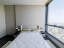Modern bedroom with a large window offering a city view and minimalistic decor