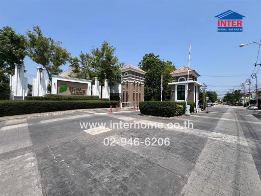 Elegant gated community entrance with security booth and lush greenery