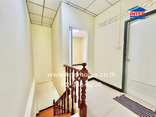 Bright hallway with wooden staircase and decorative ceiling