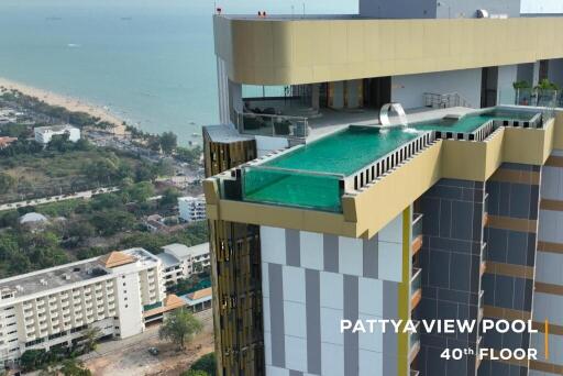 Aerial view of a high-rise building with a rooftop pool overlooking the sea