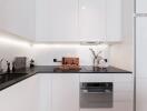 Modern kitchen with white cabinetry and black countertops