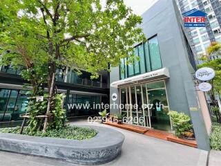 Modern commercial building exterior with lush greenery and retail shops