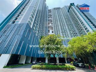 Modern high-rise residential buildings with lush landscaping and clear blue sky