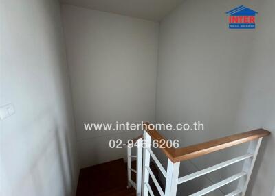 Small bedroom space with open door and wooden railing