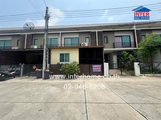 Exterior view of a row of townhouses with a for sale sign