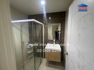 Modern bathroom with shower and glass door, featuring marble walls and wooden vanity