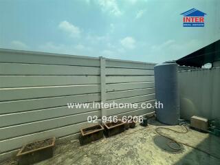 Outdoor area of a building with a water tank, discarded items, and planters