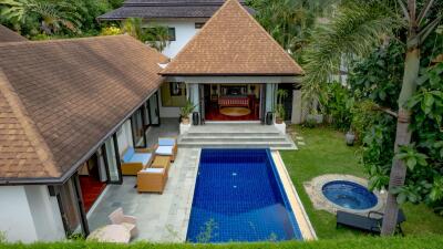 Aerial view of a luxurious house with a swimming pool surrounded by lush greenery